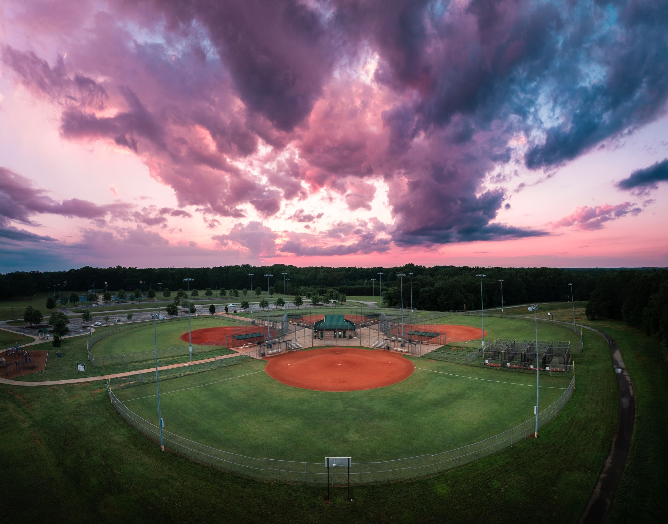 Dramatic cloud-filled sunset over aerial view of ball fields