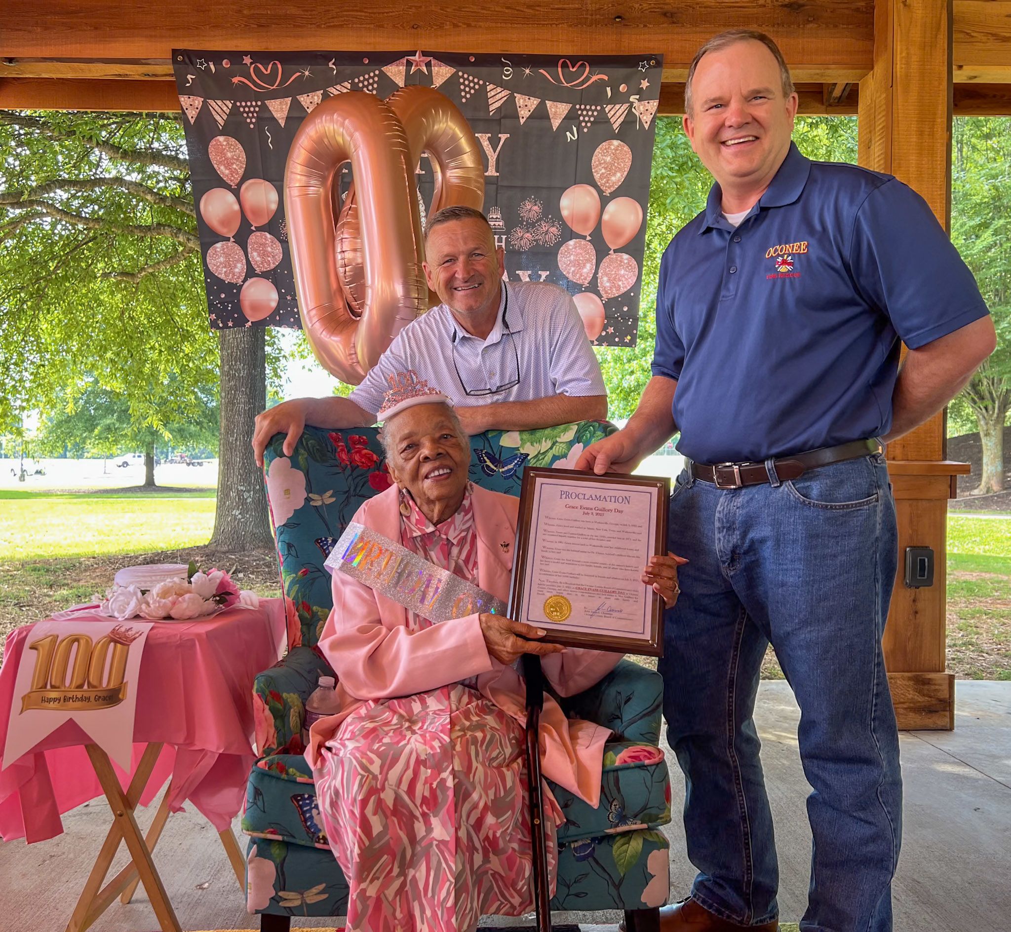 Chairman Daniell and Commissioner Saxon present proclamation to 100-year-old community member