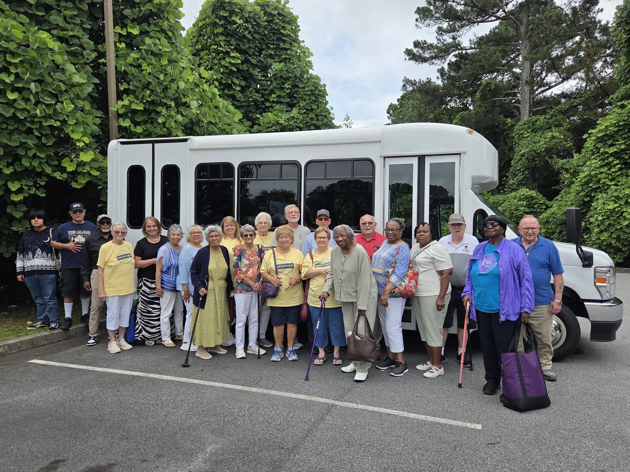 Senior Center members standing in front of their bus on a field trip