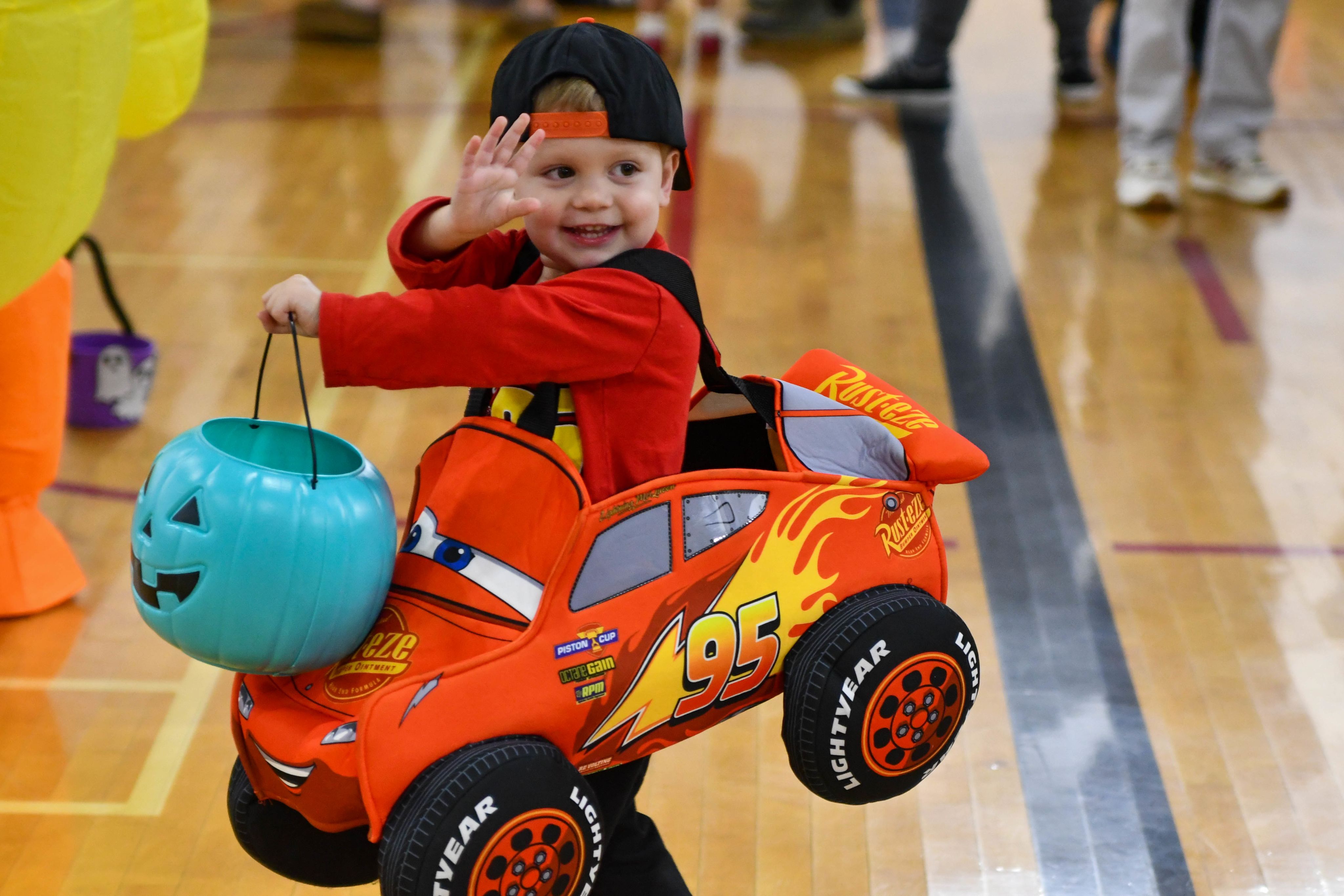Young child in costume at trick-or-treat event with teal bucket