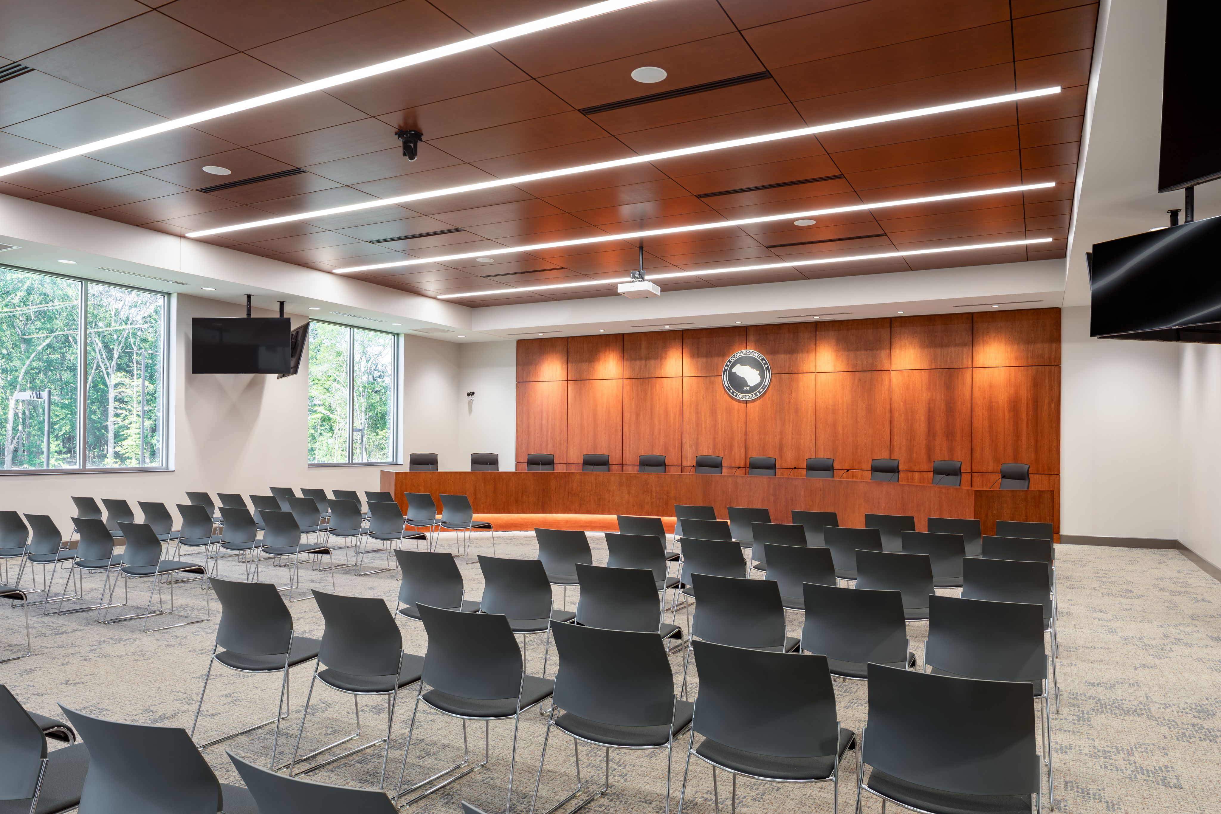 Oconee County Board of Commissioners Chambers with county seal on wall behind seats on dais and chairs for audience